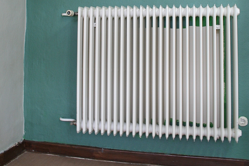 white german radiator mounted on a blue wall